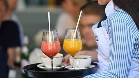 Eine Kellnerin trägt ein Tablett mit Getränken. 