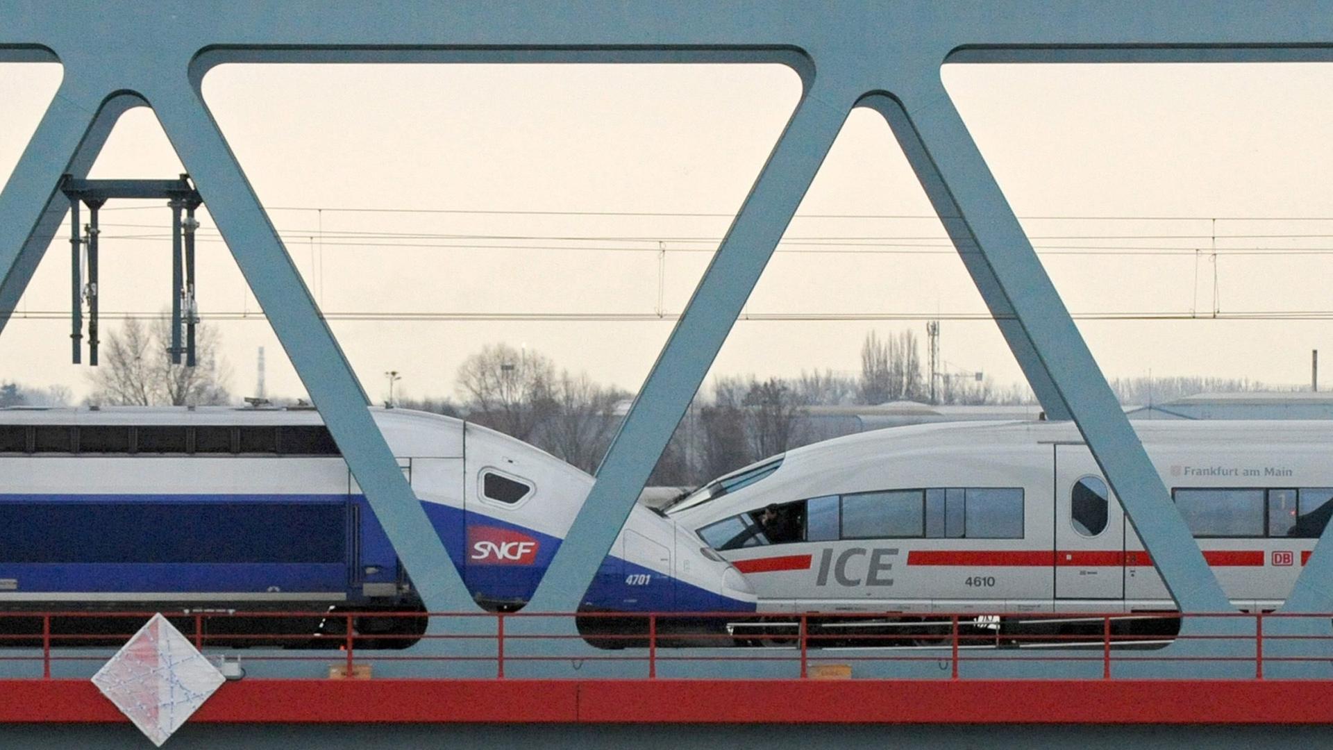 Ein TGV und ein ICE überqueren gegenläufig eine Eisenbahnbrücke aus Stahl.