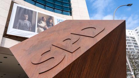 Vor einem Bürogebäude ist ein Würfel aus Metall. Das Metall ist rostig. Darauf sind drei Buchstaben: S, P und D. Es ist das Willy-Brandt-Haus, die Bundesgeschäftsstelle der SPD in Berlin.