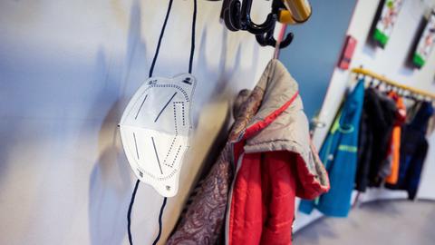 Eine FFP2-Maske, hängt an Garderobenhaken vor einem Unterrichtsraum der Vorbereitungsklasse 4 in der Ameisenbergschule. 