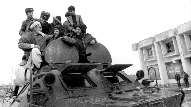 Afghanische Männer verbrüdern sich mit sowjetischen Sodlaten auf einem sowjetischen Panzer, aufgenommen in Hairhana im März 1980. 