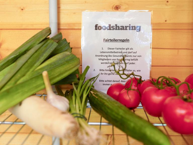 Lauch, eine Gurke und Tomaten liegen in einem Fach, dahinter hängt ein Zettel, auf dem "foodsharing" steht.