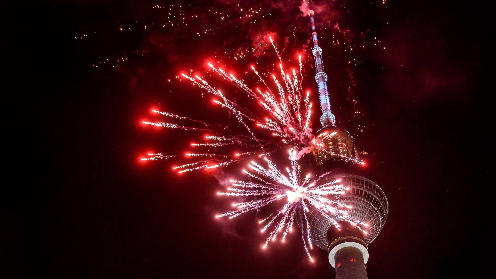 Rotes Feuerwerk explodiert vor dem Berliner Fernsehturm. 
