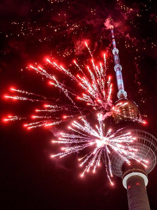 Rotes Feuerwerk explodiert vor dem Berliner Fernsehturm. 