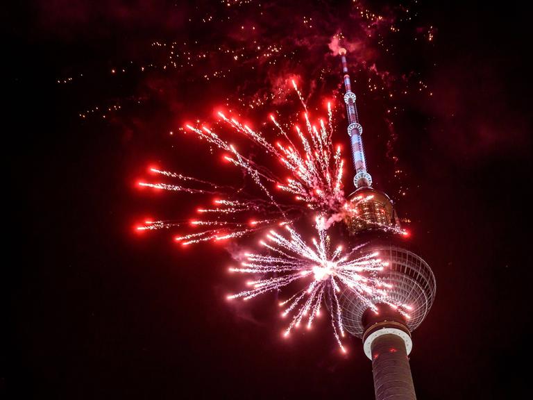 Rotes Feuerwerk explodiert vor dem Berliner Fernsehturm. 