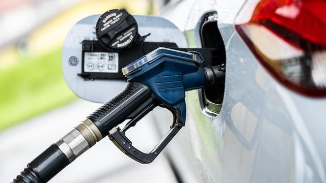 Ein Auto wird an einer Zapfsäule mithilfe eines Tankrüssels an einer Tankstelle betankt.