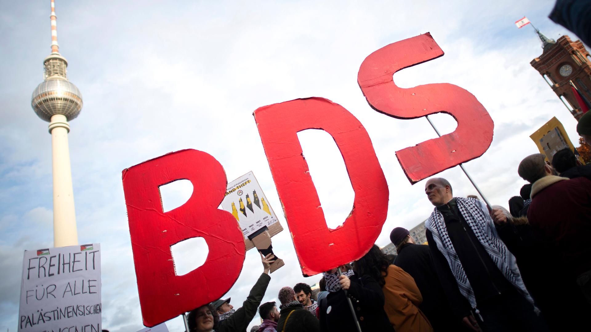 Demonstranten halten auf die roten Buchstaben BDS in die Höhe. 