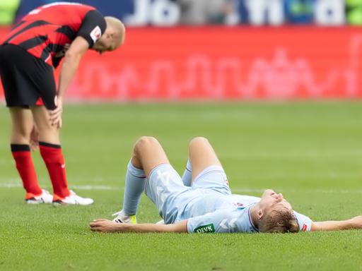 Timo Hübers (1. FC Köln) liegt nach dem Schlusspfiff erschöpft auf dem Rasen, links ist Sebastian Rode (Eintracht Frankfurt) ebenfalls müde. 