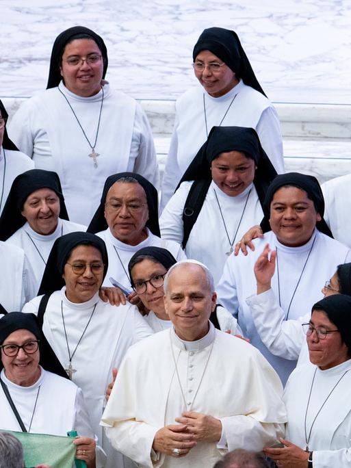 Papst Leo XIV. steht bei einer Generalaudienz umgeben von weiß gekleideten Nonnen.