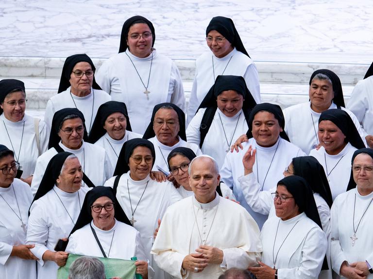 Papst Leo XIV. steht bei einer Generalaudienz umgeben von weiß gekleideten Nonnen.