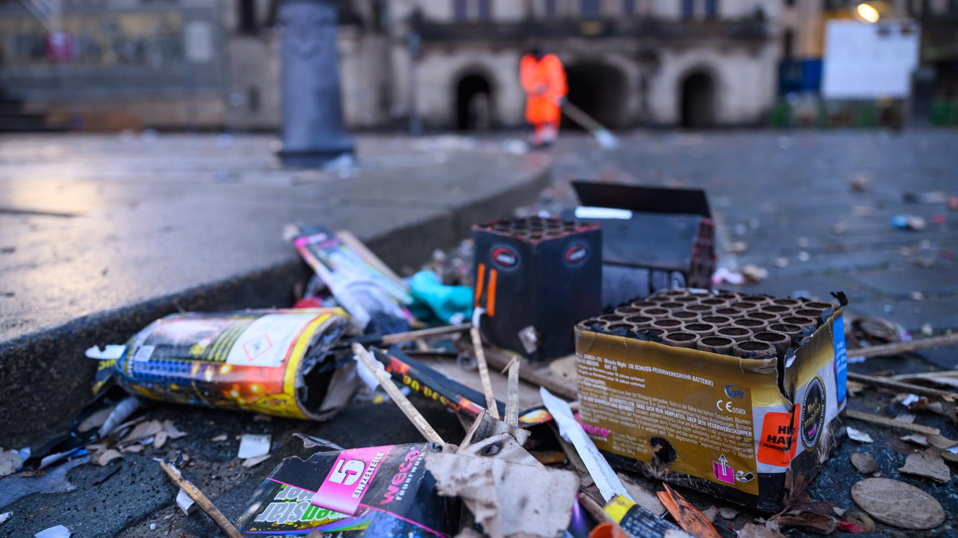 Ein Mitarbeiter der Dresdner Stadtreinigung räumt am Neujahrsmorgen in der historischen Altstadt auf dem Schlossplatz Müll weg. Im Vordergrund sind viele ausgebrannte Raketen und Feuerwerksbatterien zu sehen. 