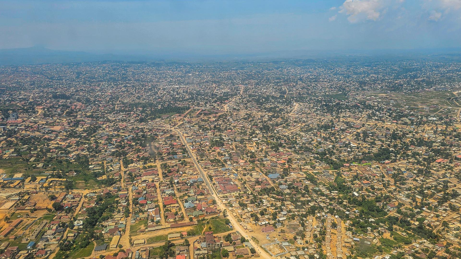 Luftaufnahme der Region um Goma im Kongo. Kleine Häuser und helle, sandinge Strassen sind zu erkennen.