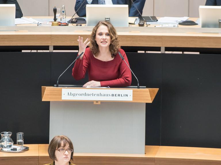Maja Lasić vor einigen Jahren bei der Aktuellen Stunde zur Schulsanierung im Berliner Abgeordnetenhaus, mittlerweile arbeitet Lasić als Lehrerin. Sie steht an einem Rednerpult und gestikuliert, im Hintergrund sind Herren an Rechnern zu sehen. 