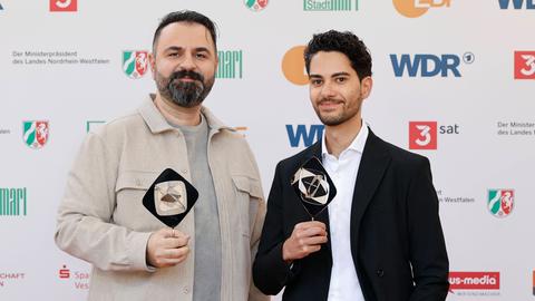 Bilal Bahadir und Cagdas Eren Yüksel bei der Verleihung des Grimme Preises. Beide haben eine Trophäe in den Händen und lächeln in die Kamera.