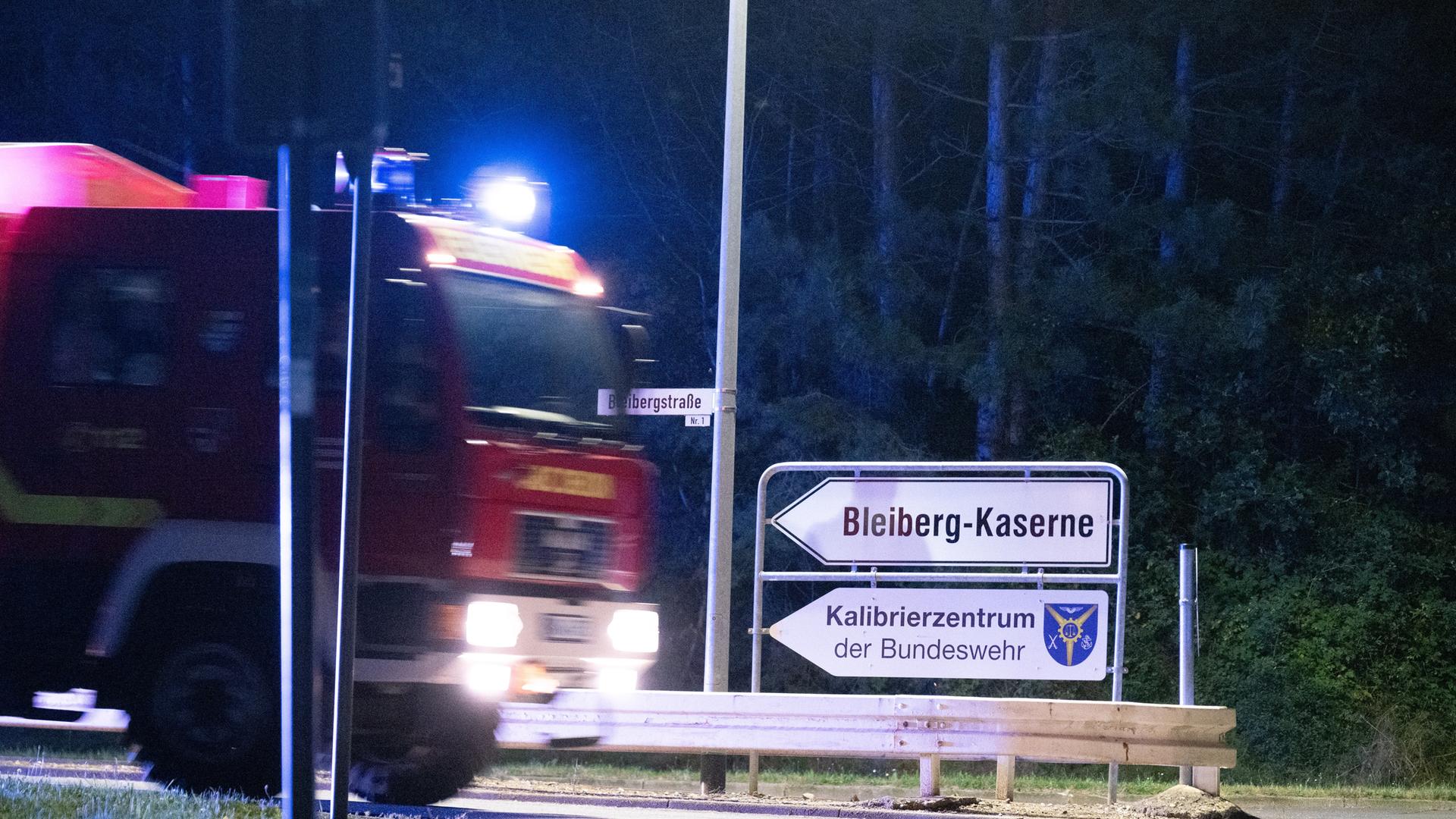 Ein Feuerwehrauto fährt eine Straße entlang, am Rand stehen zwei Schilder mit der Aufschrift "Bleiberg-Kaserne" und "Kalibrierzentrum der Bundeswehr".