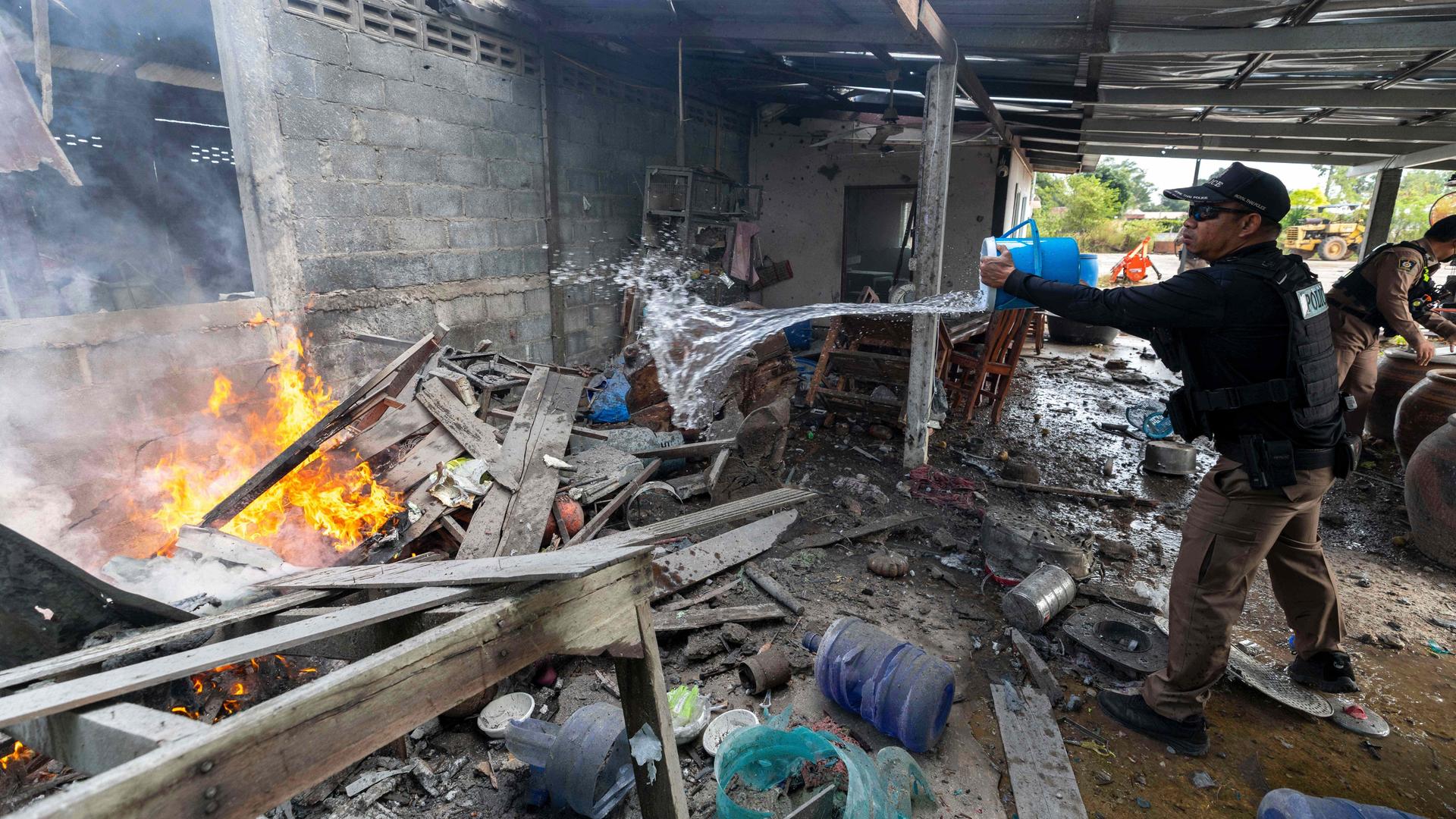 In einem zerstörten Gebäude brennnt es. Ein Mann schüttet Wasser auf die Flammen. In einem zerstörten Gebäude brennnt es. Ein Mann schüttet Wasser auf die Flammen.