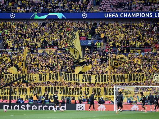 Rheinmetall-Sponsoring: Fans von Borussia Dortmund halten vor dem Championsleague-Finale gegen Real Madrid ein Spruchband "Rheinmetall. Mit dem Fußball zum Saubermann-Image?" in die Höhe.