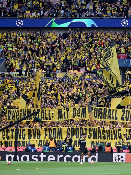 Rheinmetall-Sponsoring: Fans von Borussia Dortmund halten vor dem Championsleague-Finale gegen Real Madrid ein Spruchband "Rheinmetall. Mit dem Fußball zum Saubermann-Image?" in die Höhe.