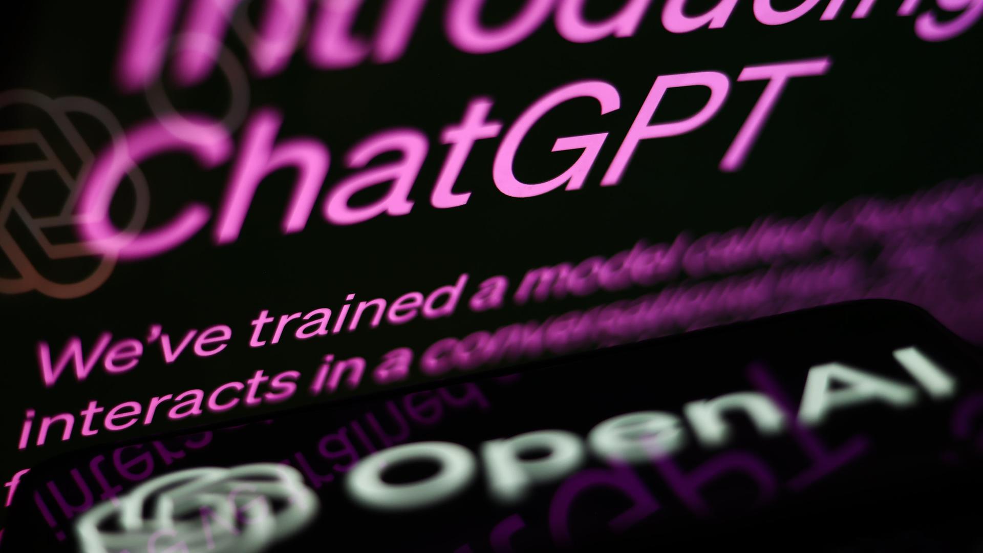 Die ChatGPT-Website ist auf dem Bildschirm eines Laptops und das OpenAI-Logo auf dem Bildschirm eines Telefons zusehen.