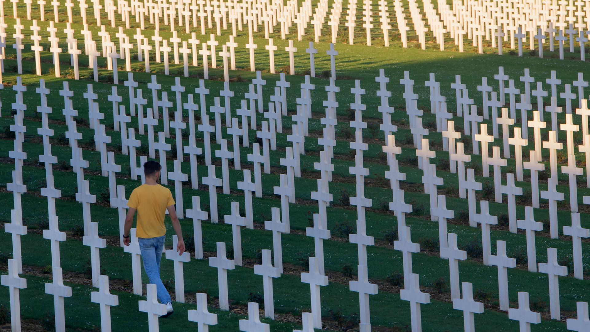 Ein Mann geht entlang weißer Kreuze über die Gedenkstätte Verdun, Schlachtfeld des Ersten Weltkrieg