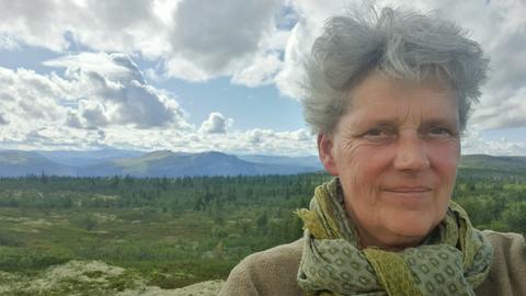 Selbstporträt von Ulrike Fokken. Im Hintergrund sind Berge zu sehen.