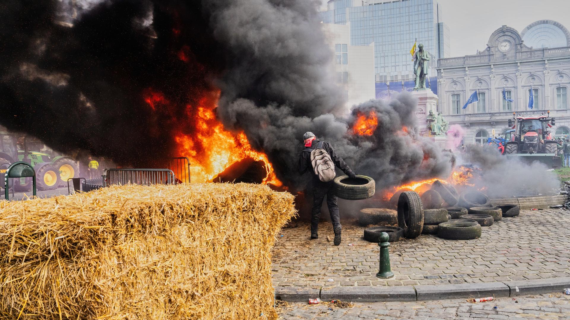 Ein Demonstrant zündet einen Heuballen an und wirft Reifen in das Feuer. Ein Demonstrant zündet einen Heuballen an und wirft Reifen in das Feuer.