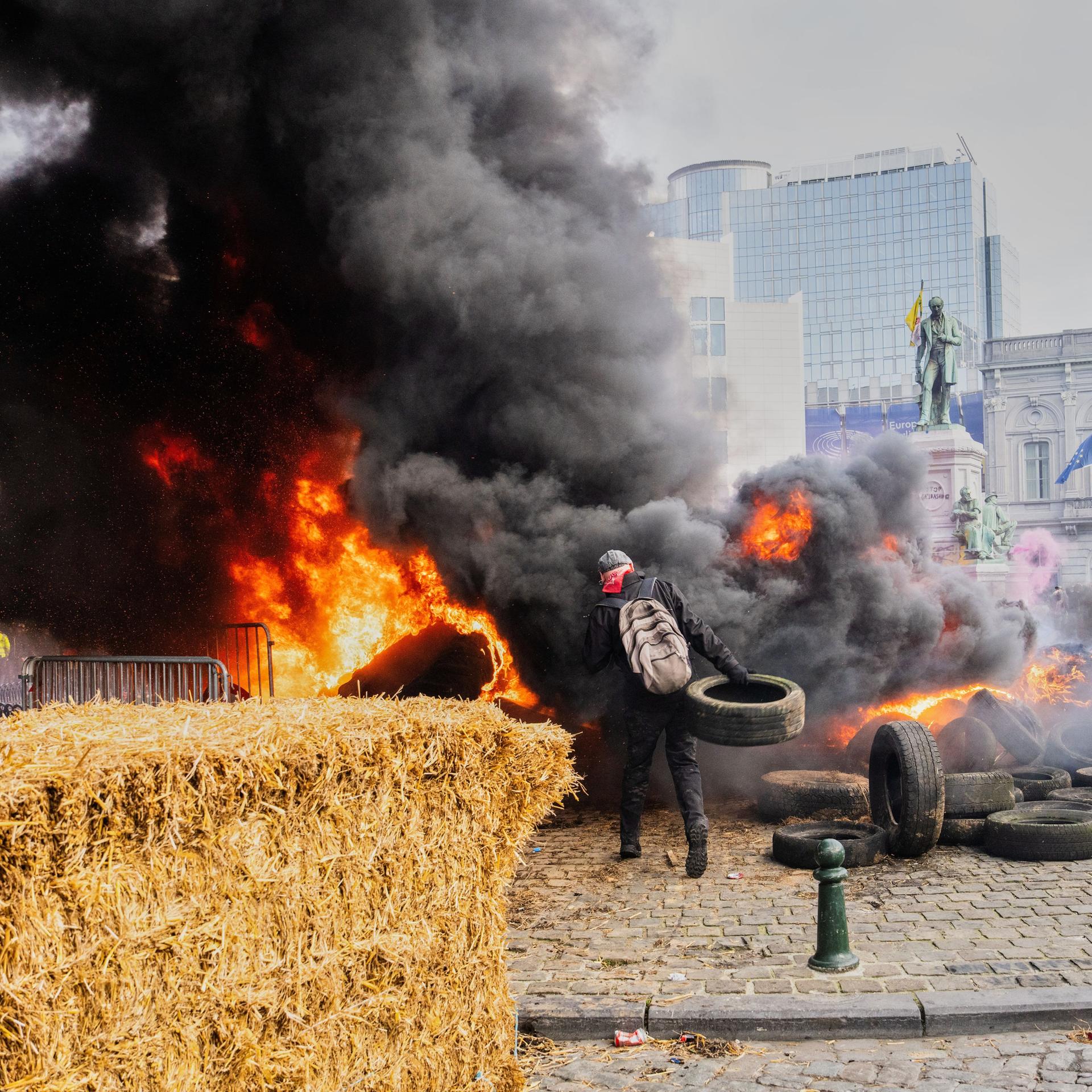 Ein Demonstrant zündet einen Heuballen an und wirft Reifen in das Feuer.
