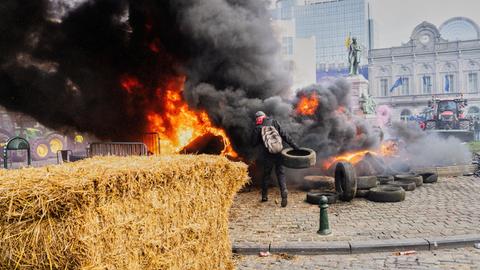 Ein Demonstrant zündet einen Heuballen an und wirft Reifen in das Feuer.