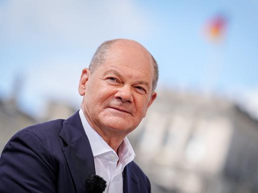 Bundeskanzler Olaf Scholz (SPD) fotografiert beim ARD-Sommerinterview im «Bericht aus Berlin». Im Hintergrund ist der Reichstag zu sehen.