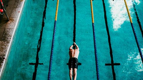 Ein Schwimmer springt ins Schwimmbecken