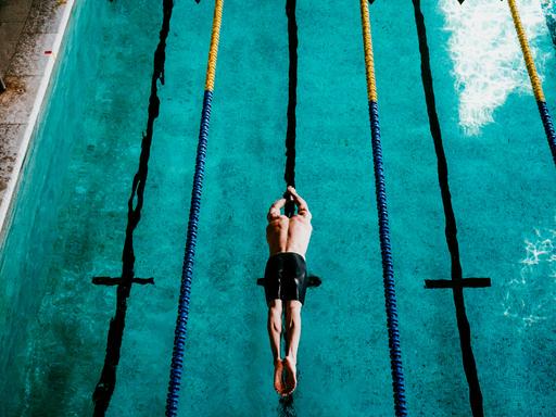 Ein Schwimmer springt ins Schwimmbecken