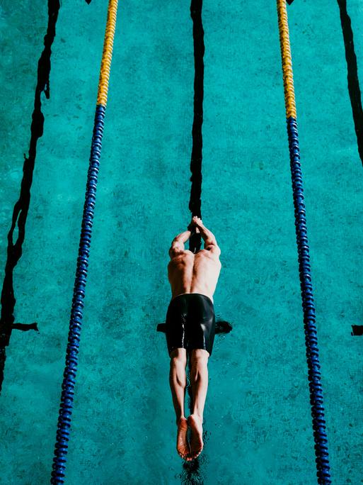 Ein Schwimmer springt ins Schwimmbecken