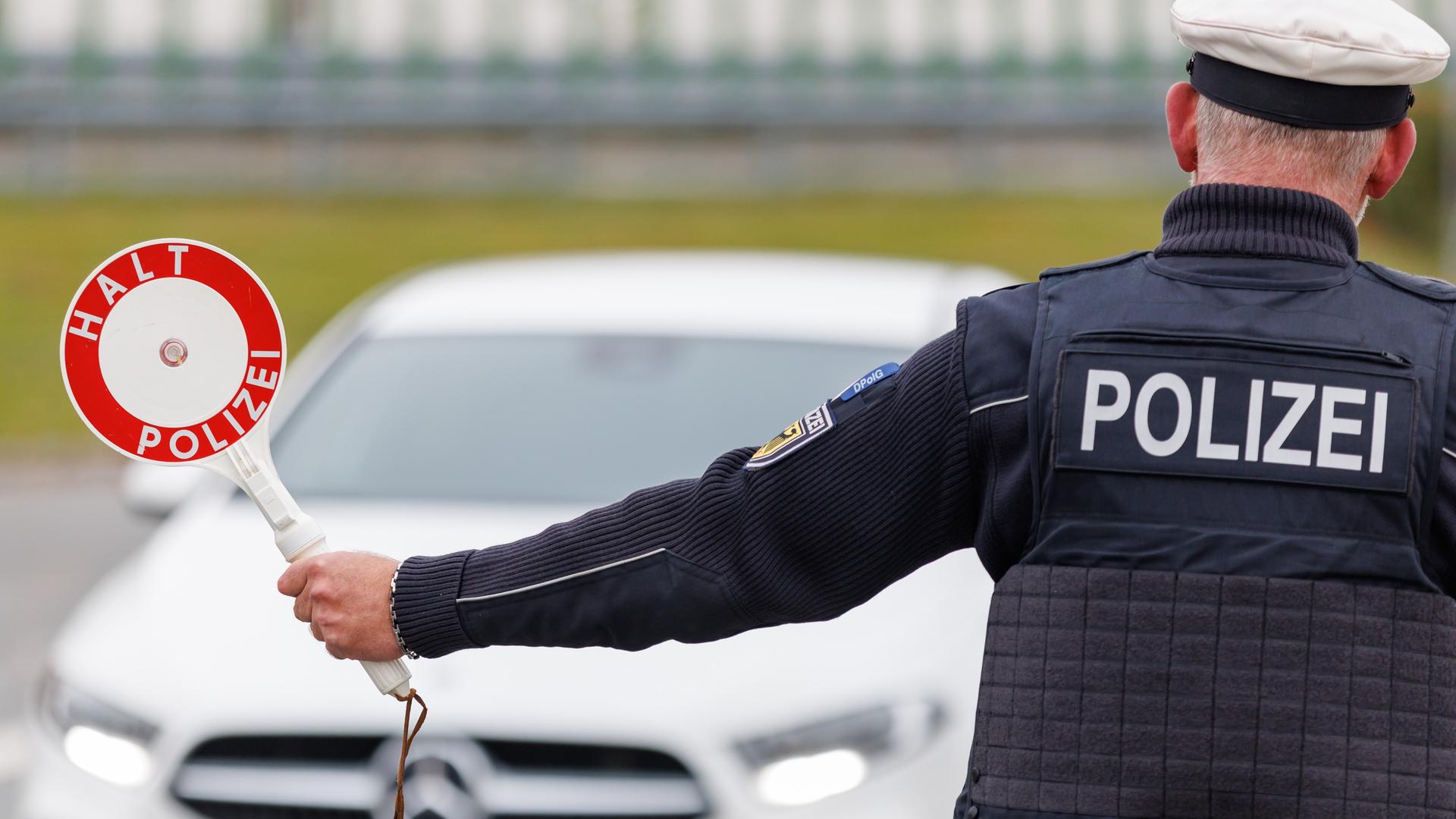 Ein Beamter der Bundespolizei winkt ein Auto mit einer Kelle aus dem Verkehr.