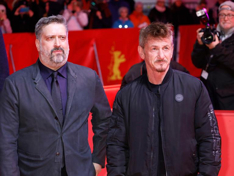 Aaron Kaufman und Sean Penn stehen auf dem Roten Teppich bei der Berlinale und zeigen sich der Presse. Kaufman links trägt Bart und hat graue Haare, er trägt ein eng sitzendes Sakko und Krawatte. Penn steht rechts, er hat strubbelige Haare, trägt eine sportliche dunkle Jacke.