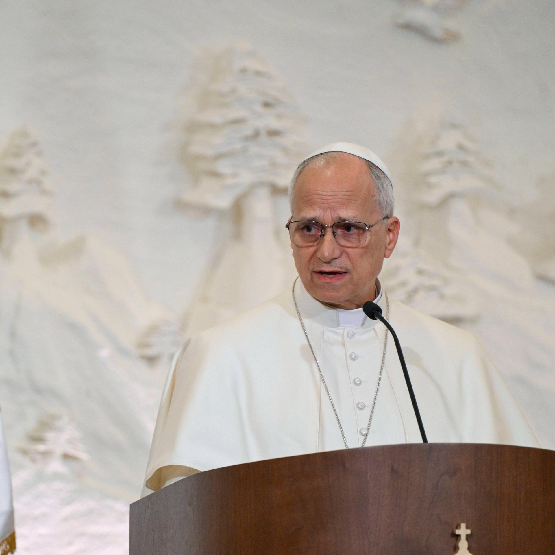 Der Papst Leo XIV steht an einem Redenerpult.