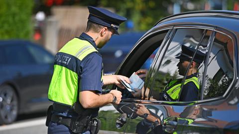Polizisten kontrollieren Fahrzeuge und Fahrzeugpapiere. 