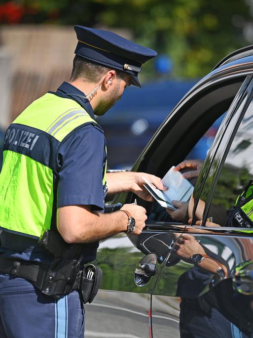 Polizisten kontrollieren Fahrzeuge und Fahrzeugpapiere. 