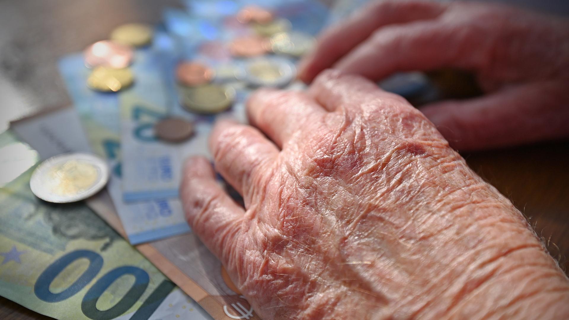 Die Hände einer älteren Person, die Geldscheine und Münzen sortiert Die Hände einer älteren Person, die Geldscheine und Münzen sortiert