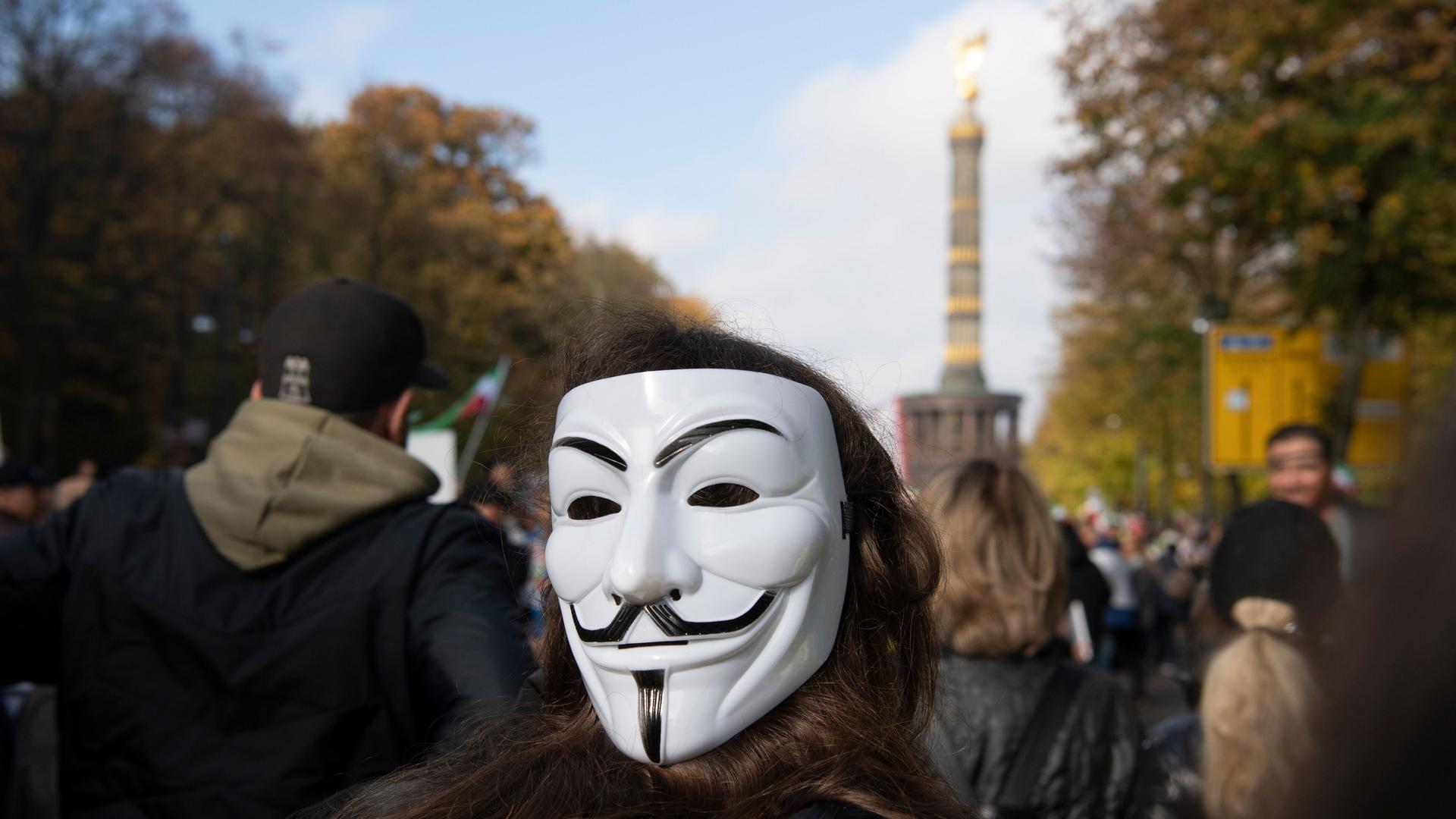 Eine Teilnehmerin der Großdemonstration "Solidarität mit den Protestierenden im Iran" trägt am Großen Stern in eine Guy-Fawkes-Maske. Vom Großen Stern aus ziehen sie durch das Regierungsviertel.