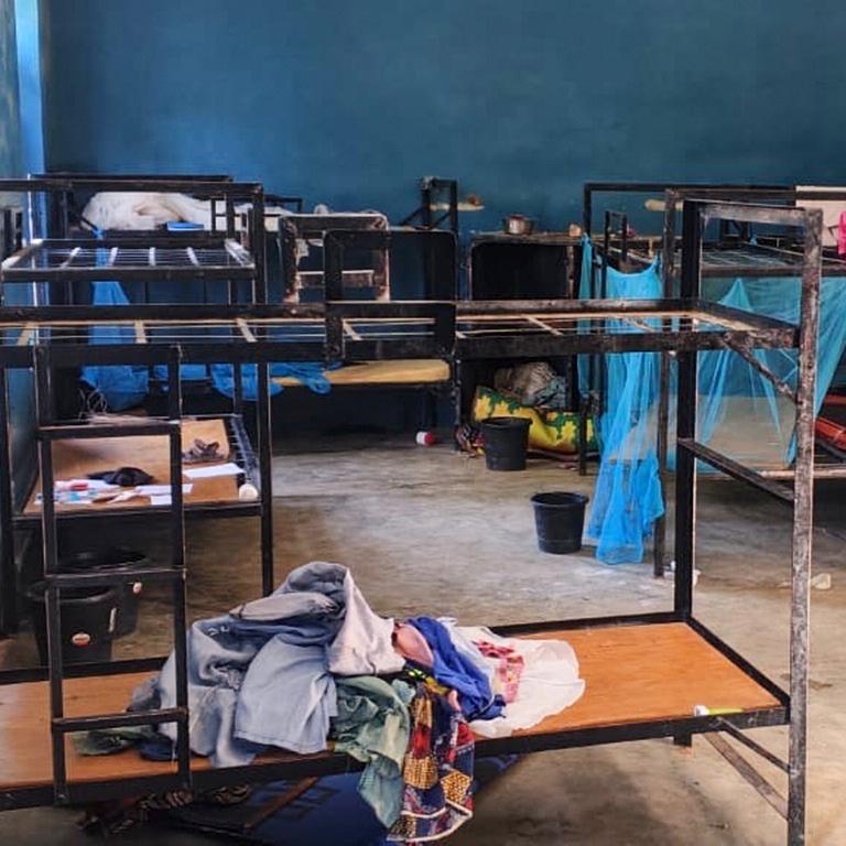 Blick in einen Schlafraum mit leeren Stockbetten. darauf löiegen zurückgelassene Kleider. 