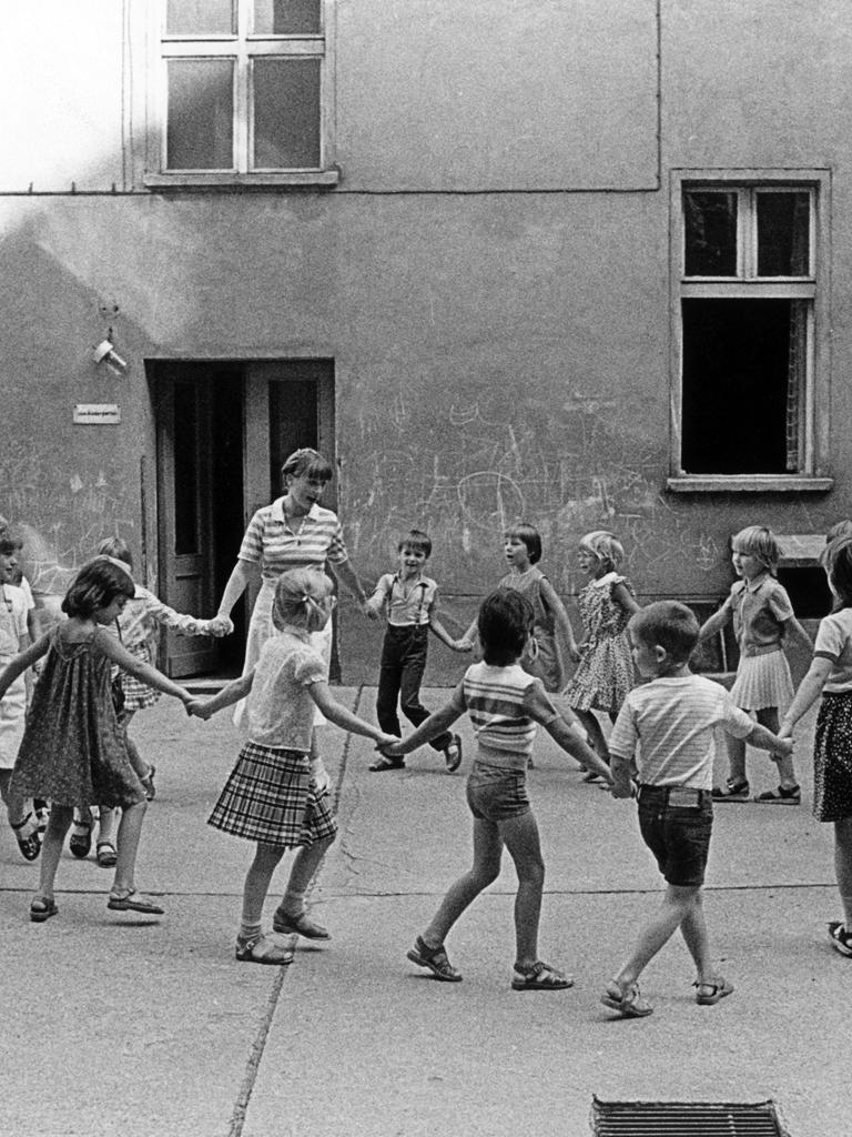 Kinder und ihre Erzieherin bei einem Kreisspiel im Hinterhof eines Kindergartens in Ostberlin, aufgenommen im März 1985.