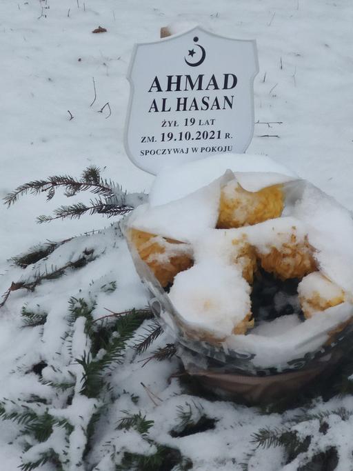 Ein von Schnee bedecktes Grab mit Namenstafel, die an einen an der Grenze zwischen Polen und Belarus gestorbenen Geflüchteten erinnert.