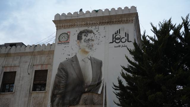 An einem Haus ein Bild von Assad, man sieht deutlich Kampfspuren und Einschusslöcher.