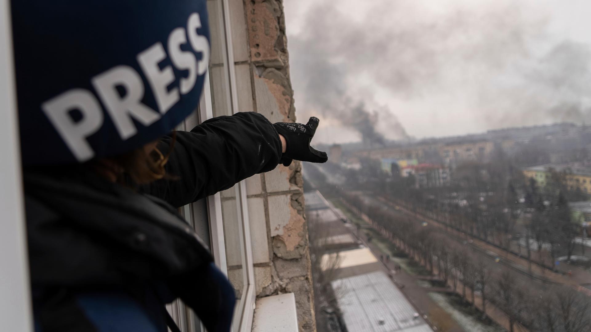 Pressefototgraf Evgeniy Maloletka zeigt auf eine Rauchsäule im ukrainischen Mariupol, die von einem Entbindungskrankenhaus aufsteigt.