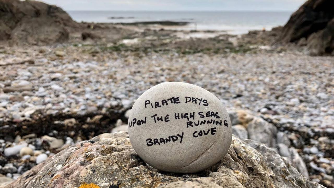Ein Haiku-Gedicht in englisch auf einem Stein am Strand.