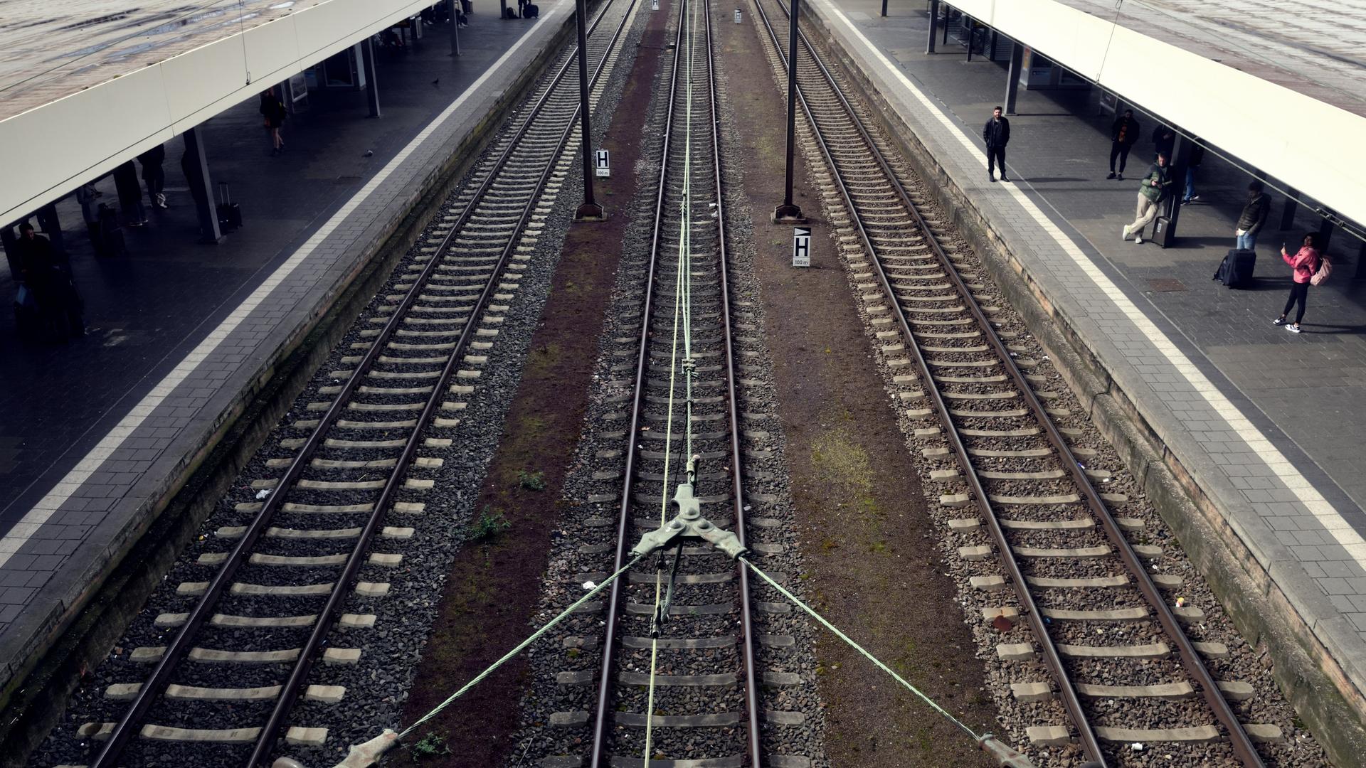 Leere Schienen und ein Bahnsteig mit wenigen wartenden Reisenden