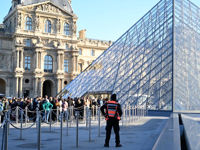 Menschen stehen Schlange, um das Louvre-Museum zu betreten. Im Pariser Louvre muss wegen baufälliger Fußböden ein Ausstellungsbereich vorsorglich und unerwartet für Besucher geschlossen werden. 