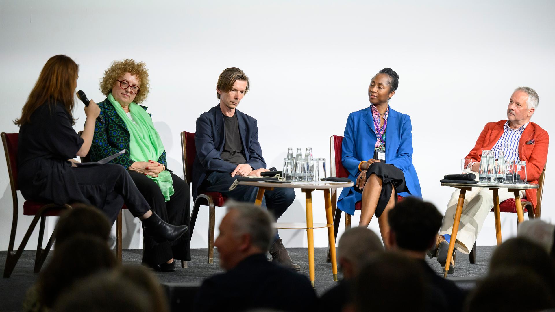 Moderatorin Saskia Trebing, Carolyn Christov-Bakargiev, künstlerische Leiterin der documenta 13, Adam Szymczyk, (documenta 14), Naomi Beckwith, künstlerische Leiterin der documenta 16, und Roger M. Buergel, (documenta 12), bei einer Podiumsdiskussion. Moderatorin Saskia Trebing, Carolyn Christov-Bakargiev, künstlerische Leiterin der documenta 13, Adam Szymczyk, (documenta 14), Naomi Beckwith, künstlerische Leiterin der documenta 16, und Roger M. Buergel, (documenta 12), bei einer Podiumsdiskussion.