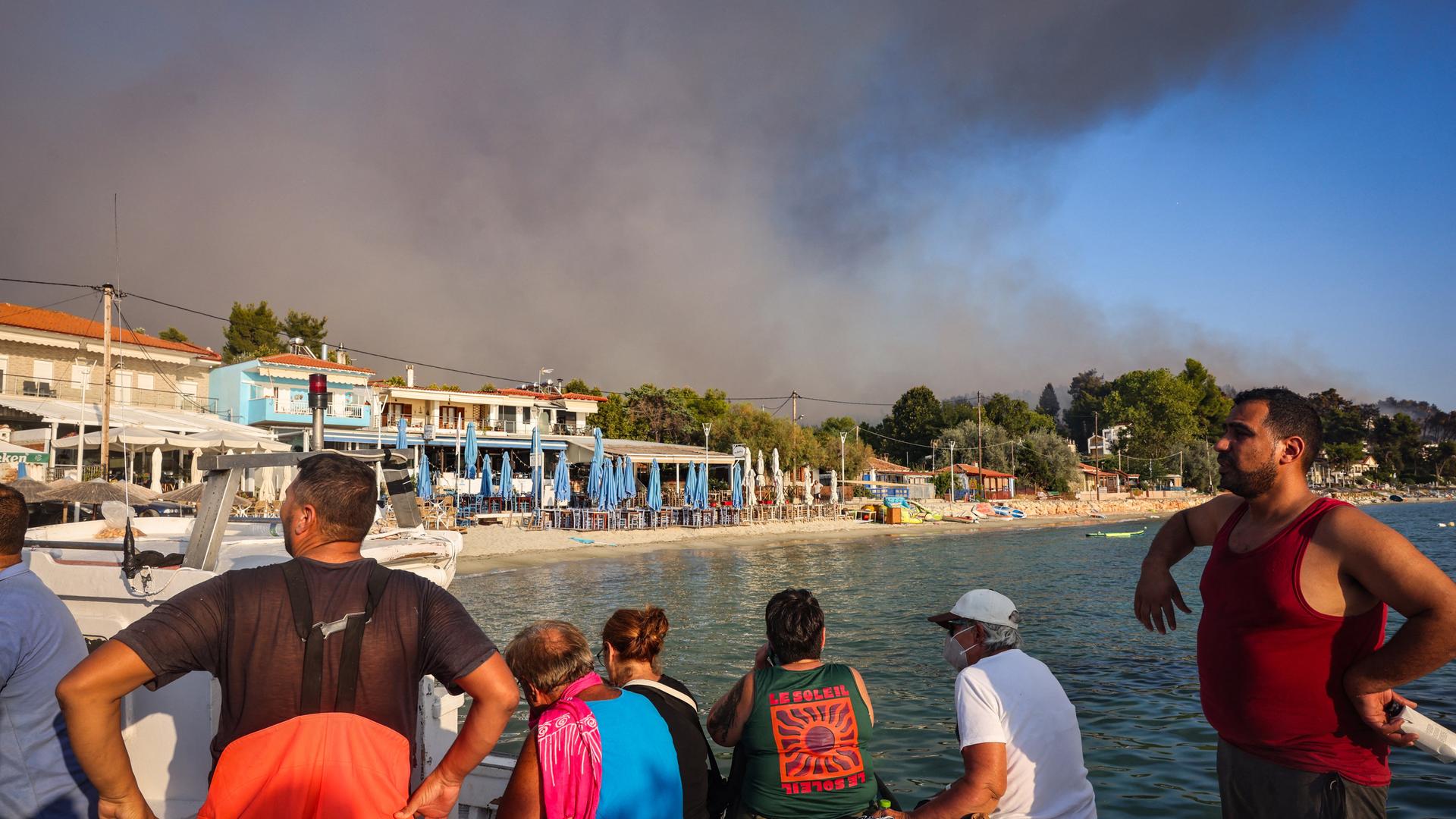 Menschen flüchten vor einem Feuer in Griechenland an den Strand. Menschen flüchten vor einem Feuer in Griechenland an den Strand.