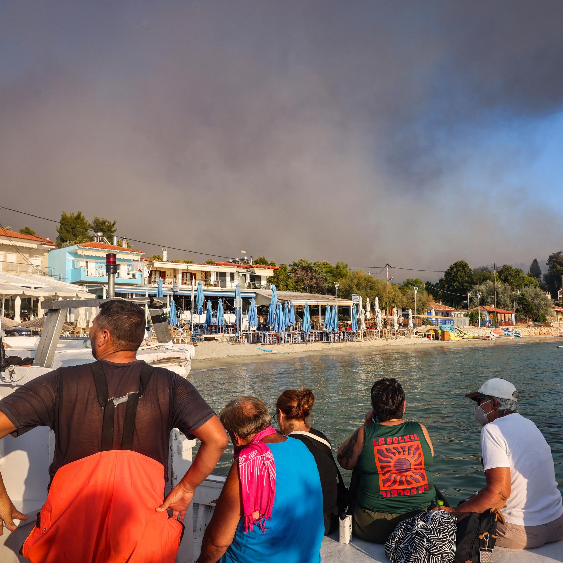 Menschen flüchten vor einem Feuer in Griechenland an den Strand.